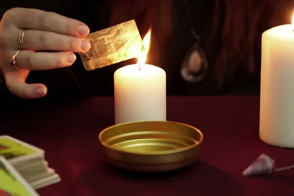 Witch is fortune teller in black mantle doing a magical ritual with ancient runes. Tarot cards, amethyst stone, white candles on dark mystic background. Occult, esoteric, divination and wicca concept Royalty Free Stock Images