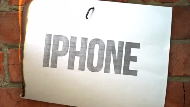 白色A4尺寸的表上的铭文 背景是橙色砖墙 黑字Iphone的纸烧焦了 冒烟变成了灰烬 贸易战的概念 — 图库视频影像