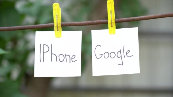 在模糊背景上黄色衣服上的白色贴纸上刻字 左边是Iphone 右边是谷歌 上面写着 的金属棒 贸易战的概念 — 图库视频影像