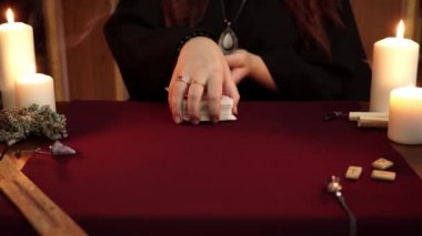 Bir cadı, siyah cüppeli falcıdır. Tarot kartları, eski rünler ve beyaz mumlar. Gizli, ezoterik, kehanet ve wicca kavramı. Mistik ve vintage arka plan.