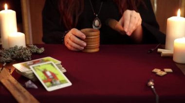 Bir cadı siyah manto lu falcı harç ezme ve havaneli kullanarak sallar pelin koymak. Büyülü bir ritüel. Tarot kartları, masada beyaz mumlar. Gizli, ezoterik, kehanet ve Wicca kavramı.