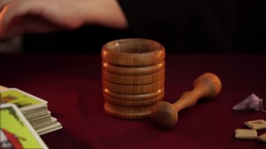 Bir cadı siyah manto lu falcı harç ezme ve havaneli kullanarak sallar pelin koymak. Büyülü bir ritüel. Tarot kartları, masada beyaz mumlar. Gizli, ezoterik, kehanet ve Wicca kavramı.
