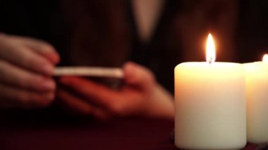 Bir cadı siyah Robe içinde falcı Tarot kartı gösterir. Masada beyaz mumlar var. Gizli, Esoterik, kehanet ve Wicca kavramı. Çeviri: Chariot.