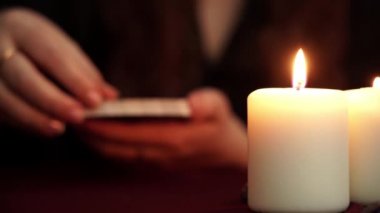 Bir cadı siyah Robe içinde falcı Tarot kartı gösterir. Masada beyaz mumlar var. Gizli, Esoterik, kehanet ve Wicca kavramı. Çeviri: yıldız.