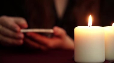 Bir cadı siyah manto tarot kartı gösterir falcı olduğunu. Masada beyaz mumlar var. Gizli, ezoterik, kehanet ve wicca kavramı. Çeviri: Adalet.
