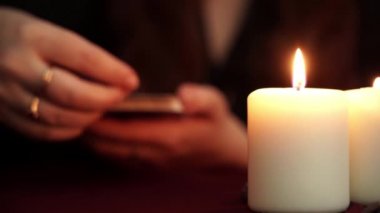 Bir cadı siyah cüppe tarot kartı göstermek falcı olduğunu. Masada beyaz mumlar var. Gizli, ezoterik, kehanet ve wicca kavramı. Çeviri: Dünya.