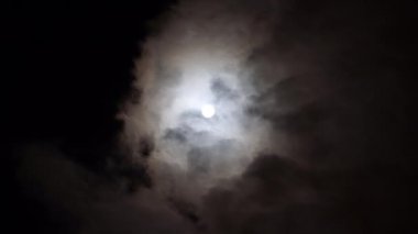 Bulutlu bir günde gece mavisi gökyüzünde romantik dolunay manzarası. Hacim kümülüs bulutları arasında parlak beyaz ay. Bulutlar gökyüzünde hızlı koşar. Ezoterik zaman.