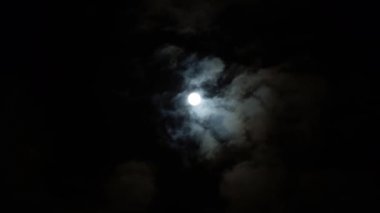 Bulutlu bir günde gece mavisi gökyüzünde dramatik büyük ay. Hacim kümülüs bulutları arasında parlak beyaz ay. Aydan gelen parıltı. Bulutlar gökyüzünde yavaş akıtır. Kehanet zamanı.