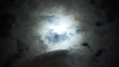Bulutlu bir günde gece mavisi gökyüzünde dramatik dolunay görünümü. Hacim kabarık bulutlar arasında parlak beyaz ay. Bulutlar gökyüzünde yavaş akıtır. Sihirli zaman.