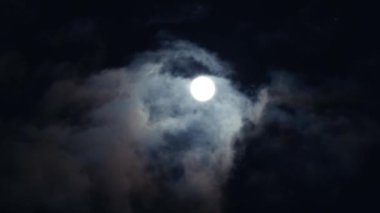 Bulutlu bir günde gece mavisi gökyüzünde romantik gece yarısı ayı. Gri hacimli kümülüs bulutları arasında parlak beyaz ay.