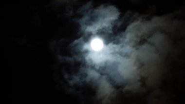 Bulutlu bir günde gece mavisi gökyüzünde dramatik dolunay. Hacim kabarık bulutlar arasında parlak beyaz ay. Bulutlar gökyüzünde yavaş akıtır. Kurt adamlar zamanlı.