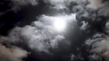 Bulutlu bir günde gece mavisi gökyüzünde dramatik ay. Kabarık kümülüs bulutları arasında parlak beyaz ay. Bulutlar gökyüzünde yavaş akıtır. Sihirli zaman.