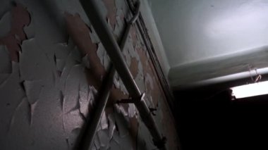 Yeşil boya çatladı ve eski bir sanayi fabrikasında soyulmuş kahverengi duvardan uzağa düştü. Eski paslı borular ve koyu siyah bir koridorda beton tavana asılı uzun bir floresan lamba.