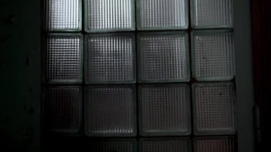 Arkalarında yansıma aydınlatma ile karanlık bir odada Cam tuğla desen pencere yakın çekim. Tasarım arka planı için soyut blok duvarlar. Iç cam yüzeyi. SSCB'den güvenlik konsepti.