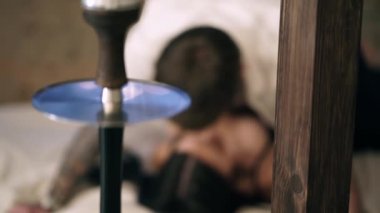 Beyaz buruşturulmuş gömlek lüks Kafkas adam yatak odasında bir bej ahşap yatakta iç çamaşırı siyah saçlı çekici bir seksi kadın bakar. Bir kadının üstünde ki bir adam. Masada siyah nargile.