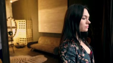 Elinde saat ve bir dövme ile beyaz gömlek sakallı beyaz bir adam ipek bir cüppe güzel bir kadının arkasında gelir ve bir kanepe ile sarı bir oturma odasının arka planda gözlerini kapatır.