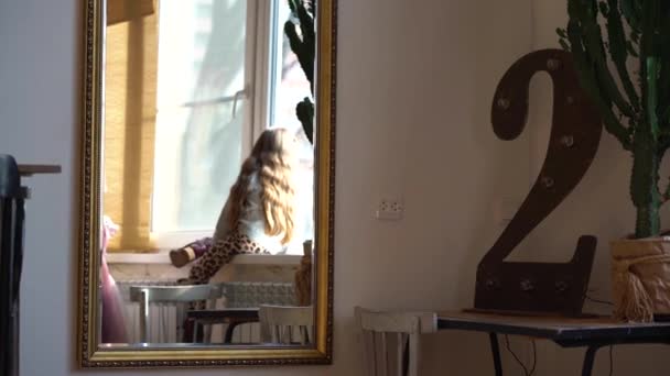 바지와 보라색 신발에 머리를 소녀에 거울을 소녀는 창턱위로 올라가 플라스틱 — 비디오