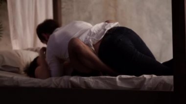 Beyaz buruşmuş gömlek ve koyu pantolon ve kırmızı iç çamaşırı seksi bir kadın bir adam beyaz pamuklu yatakta yatıyor. Romantik bir ortamda yatak odasında çift. Seks kavramı.