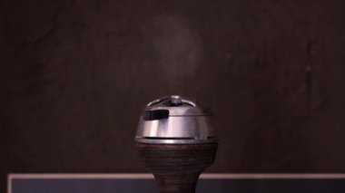 Metal bir kapta sıcak kırmızı kömürler. Duman bulutu kahverengi bulanık koyu arka plan yakın çekim üzerinde bir kil kase üzerinde plastik bir sapı ile kaloud dışarı uçar. Nargile elementi.