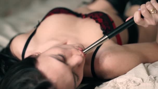 性感的女孩与黑色的头发在美丽的红色蕾丝内衣与美甲与乐趣吸烟在卧室的白色棉床上的钩子 并得到享受在家里 女人从嘴里吹烟 — 图库视频影像