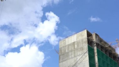 Güzel bulutlu mavi gökyüzü bir arka plan üzerinde yapım aşamasında Yüksek beton gri Sanayi binasının düşük görünümü. Güneşli bir günde yüksek katlı binalar inşa etmek için hangi şantiye.