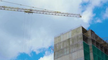 Güzel bulutlu mavi gökyüzü bir arka plan üzerinde beton Sanayi binası yakınında kendi kendine ereksiyon yüksek kule vinç Düşük görünümü. Güneşli bir günde yüksek katlı binalar inşa etmek için hangi şantiye.