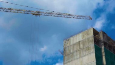 Güneş kendi ereksiyonunu aydınlatır. Yüksek kule vincinin yanındaki beton sanayi binası güzel bulutlu gökyüzünün arka planında. Büyük konut binaları inşa etmek için inşaat alanı.