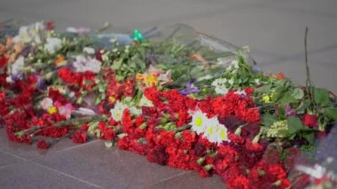 Bilinmeyen Asker Mezarı'nda Ebedi Alev anıt anıtıüzerinde kırmızı ve beyaz cenaze çiçekleri - Dünya Savaşı'nda zafer sembolü ve milyonlarca Sovyet kurbanlarının anısına insanlar anavatan savunucuları