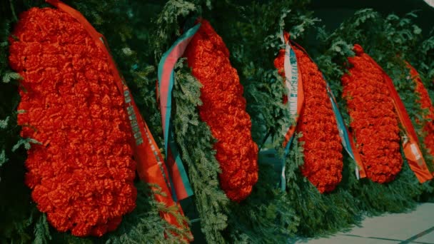 Красивые Похоронные Ритуальные Венки Красными Цветами Зеленой Елкой Лентами Могилы — стоковое видео