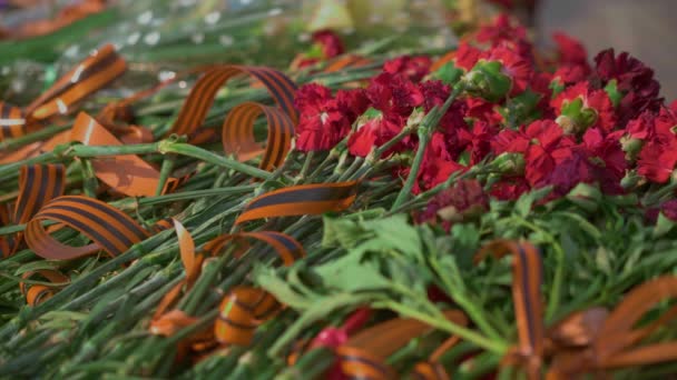 红色和绿色葬礼鲜花与圣乔治丝带在无名战士墓的永恒火焰纪念碑 象征在第二次世界大战的胜利和数百万苏联受害者纪念 — 图库视频影像