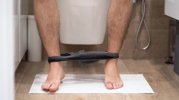 Man Met Grijs Ondergoed Zit Toiletpot Staat Witte Mat Bungelt — Stockvideo