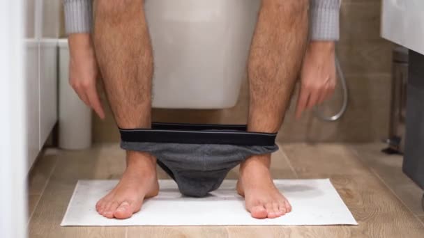 Ein Junger Mann Karierten Freizeithemd Sitzt Auf Einer Weißen Toilettenschüssel — Stockvideo