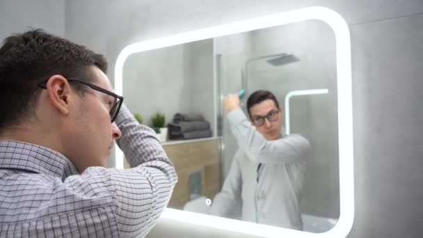 일과야 격자무늬 셔츠를 청년의 뒷모습 안경을 욕실에 거울에 기대어 머리를 — 비디오
