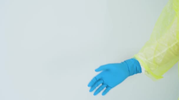 一人の男 医療用青ゴム手袋の医者は挨拶のジェスチャーを作る 医学の黄色のスーツを着て 白の背景を閉じるに対して握手のための手を握ります 安全コンセプト スペースのコピー — ストック動画