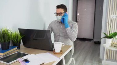 İşadamı mavi akıllı telefondan konuşuyor, iş meselelerine kara dizüstü bilgisayar kullanarak karar veriyor. Adam tek kullanımlık yüz maskesi takıyor, bardak, defter, anahtarlar, bitkilerle masaya oturuyor. Erkek covid-19 ile karantinada kalıyor.