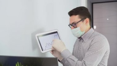 Genç işadamı yüz maskesi takıyor, müşterilerle video görüşmesi yapıyor. Gözlüklü, güvenli bir adam çevrimiçi eğitim sınıfı konferansı veriyor, döviz kuruyla ilgili müşterilere danışıyor..