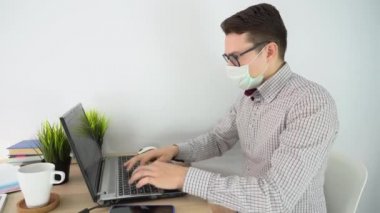 Evde internet işi. Komik iş adamı koruyucu yüz maskesi, siyah gözlük, ekose gömlek, mavi şort giyer. Adam görüntülü konuşma yapıyor, arıyor, beyaz odadaki masadaki laptopu kullanıyor. Karantina konsepti