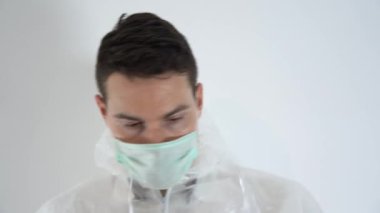 Yakışıklı esmer doktor, bulaşıcı hastalık uzmanı, beyaz koruyucu giysi, tıbbi maske, plastik gözlük takan mavi lastik eldiven, kaput, fermuar. Beyaz arkaplanda portreyi kapat.
