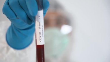 Koruyucu giysi, yüz maskesi, eldiven giyen hasta bir adam üzerinde Coronavirus Covid-19 yazan kan tüpü olduğunu gösteriyor. Yeni deneysel aşıyı aldıktan sonra iyileşme kavramı