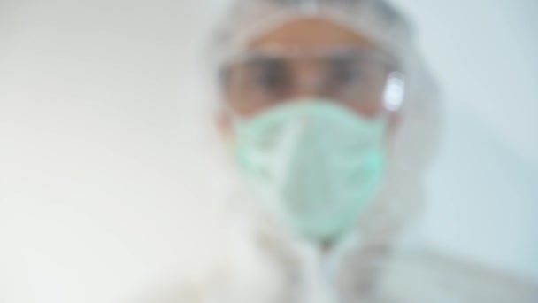 ある未知のぼやけた人は示す 白い実験室で病気のためのテスト薬を使用した後Covid 19上のガラス陰性の血液検査管を保持します 男は保護服 医療用手袋 フェイスマスクを身に着けている スペースのコピー — ストック動画