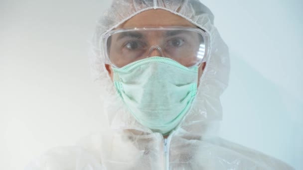男性科学者は白い保護スーツ 使い捨てゴム手袋を着用し ウイルスで動作し 手にフラスコを保持し Covid 19の閉鎖のための陰性の血液検査を示します 感染していない 病気ではないことを知っている — ストック動画