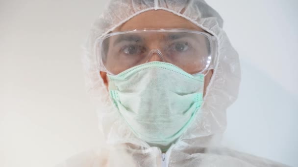 保護服 フード 医療面マスクを身に着けている若い医師は 目にしっかりと眼鏡を装着 男は手袋の手で血液と試験管を保持示しています 碑文は言いますCoronvirus 19陰性のテスト — ストック動画
