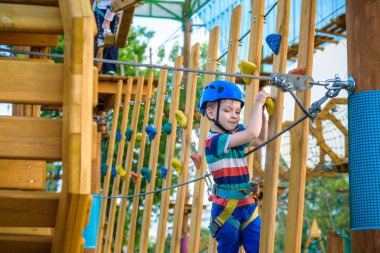 Çocuk Macera Parkı'nda eğleniyor. bir ip Bahçesi yapısında tırmanma yürümeye başlayan çocuk. bir ip Bahçesi yapısında tırmanma yürümeye başlayan çocuk. Kask ve kemer ile güvenli tırmanma aşırı spor