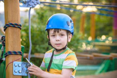 Küçük şirin çocuk aktivite bir tırmanma macera parkta yaz güneşli bir günde zevk. bir ip Bahçesi yapısında tırmanma yürümeye başlayan çocuk. Kask ve kemer ile güvenli tırmanma aşırı spor. sigorta