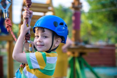 Küçük şirin çocuk aktivite bir tırmanma macera parkta yaz güneşli bir günde zevk. bir ip Bahçesi yapısında tırmanma yürümeye başlayan çocuk. Güvenli tırmanma aşırı spor kask sigorta hareket bulanık ile