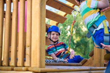 Küçük şirin çocuk aktivite bir tırmanma macera parkta yaz güneşli bir günde zevk. bir ip Bahçesi yapısında tırmanma yürümeye başlayan çocuk. Kask ve kemer ile güvenli tırmanma aşırı spor. sigorta