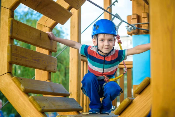 Eğleniyor ve Macera Parkı'nda oynarken, ipleri tutan ve Ahşap merdiven çıkma mutlu çocuk.