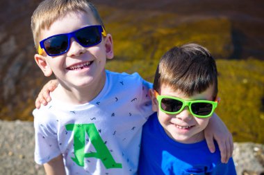 Şehir nehir ya da göl kıyısında parlak güneşli bir günde mutlu çocuk portresi. Dostluk. Yaz tatili.