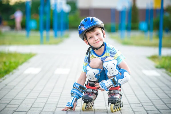 Smiling boy with inline skates and protective gear. Kid wearing protection pads for safe roller skating ride. Active outdoor sport for kids. Close up view