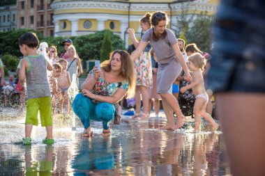 Kiev, Ukrayna 13 Ağustos 2017: Happy kids sıcak yaz gününde şehir su fıskiyede oynamak eğlenceli. Ebeveynler çocuklarıyla birlikte. Etkin aile boş, ekoloji kavramı.